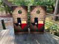 Two cornhole boards with Texas flag design on a wooden surface outdoors.