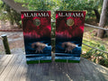 Two cornhole boards with Alabama design on a wooden surface outdoors.