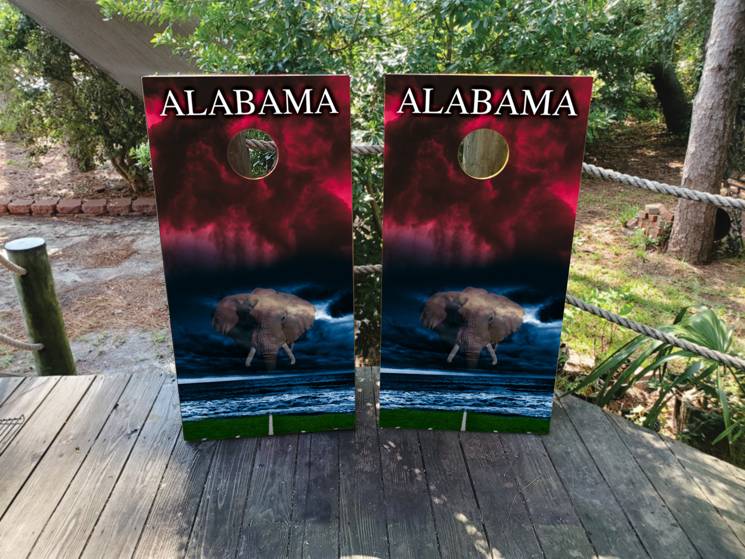 Two cornhole boards with Alabama design on a wooden surface outdoors.