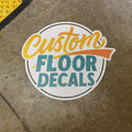 Circular logo with 'Custom Floor Decals' text on a textured surface