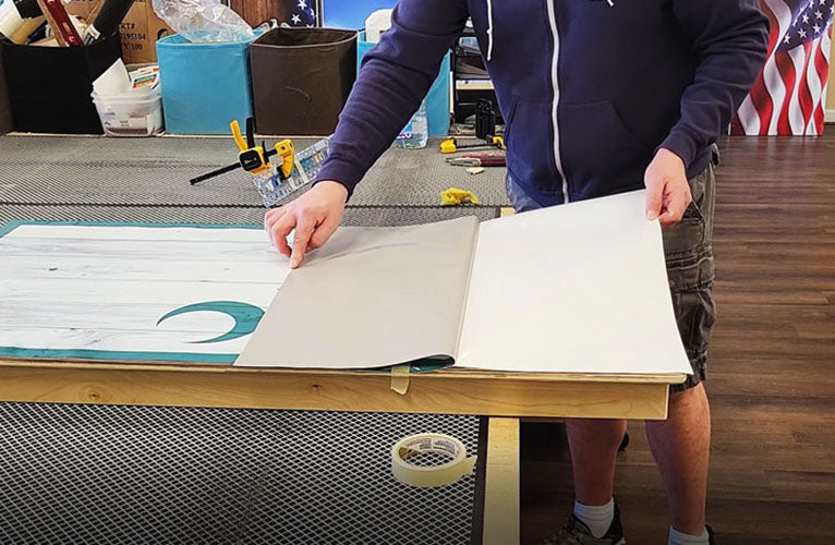 Person applying a cornhole wrap