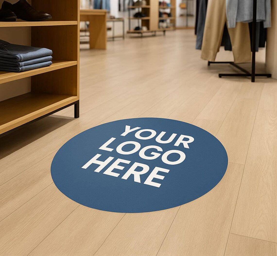 Blue circular sticker with 'YOUR LOGO HERE' text on a wooden floor in a store setting.