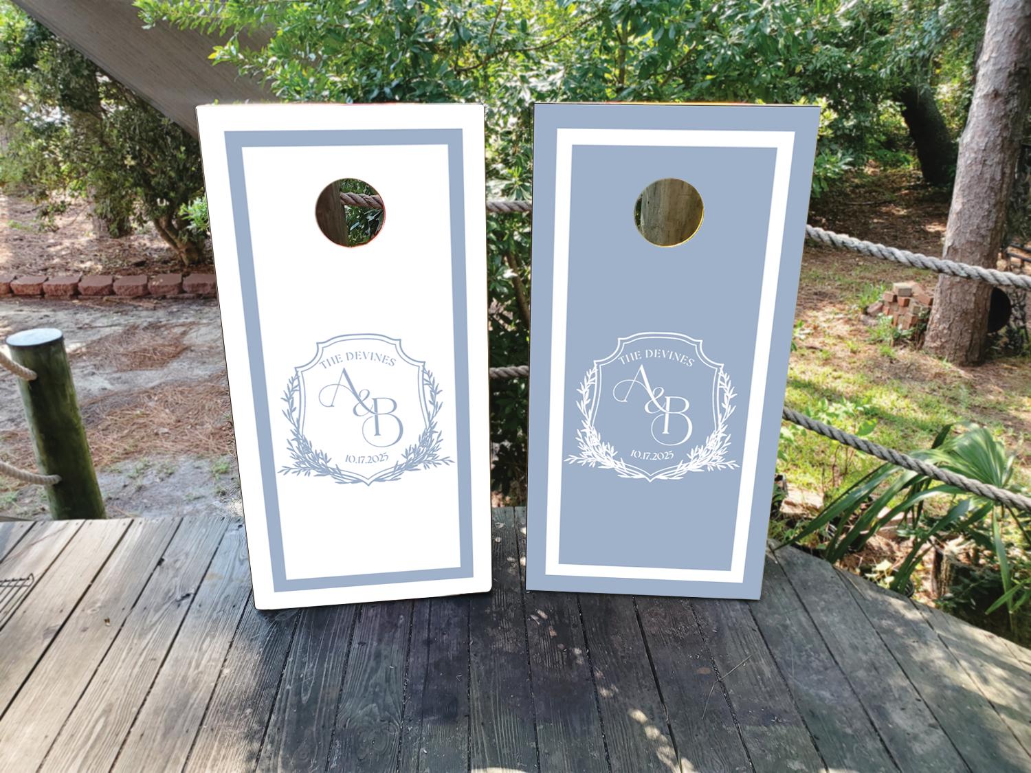 cornhole wraps in a dusty blue and white with a custom wedding crest