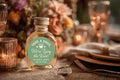 Wedding favor mini bottle with custom Take a Shot We’re Tying the Knot sticker displayed on elegant reception table
