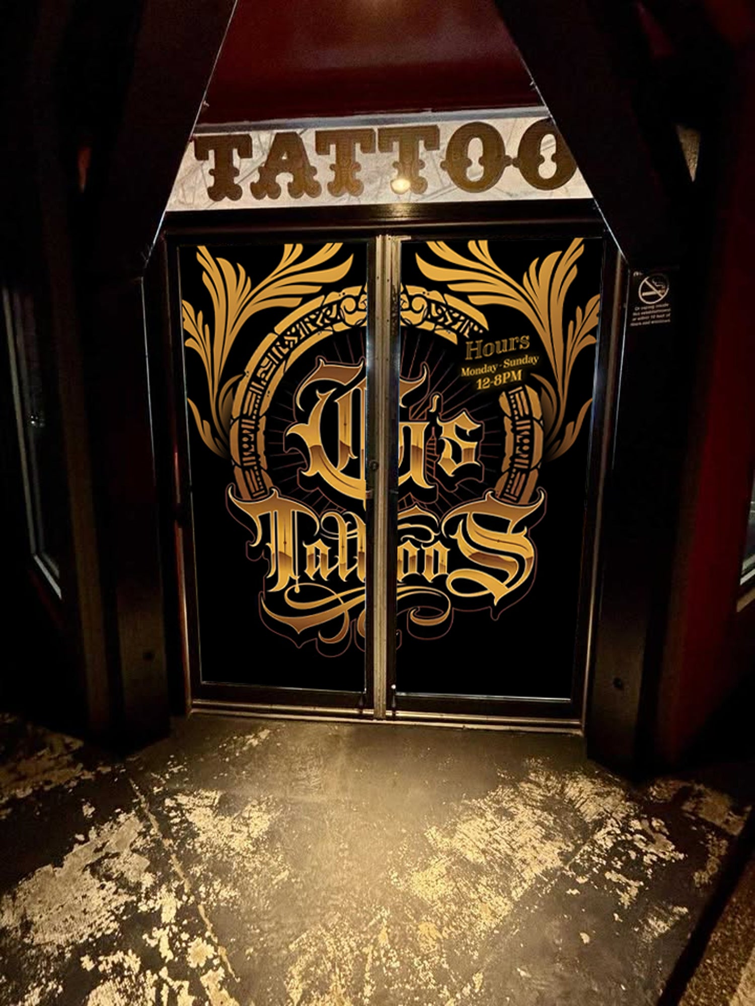 Decorative glass door with gold and white text and designs, featuring the word 'Tattoo'.