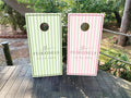 Personalized wedding cornhole wraps in pastel green and pink striped designs featuring the couple’s last name and wedding date on regulation boards