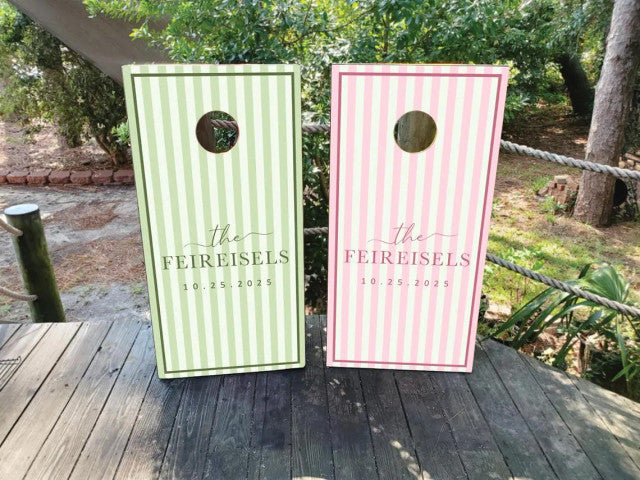 Personalized wedding cornhole wraps in pastel green and pink striped designs featuring the couple’s last name and wedding date on regulation boards